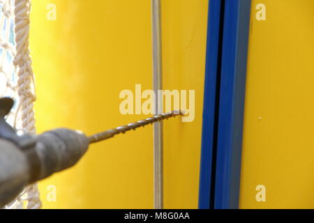 During drilling with a hammer drill, a lot of shocks and large noise are generated if the wall is solid concrete. Stock Photo