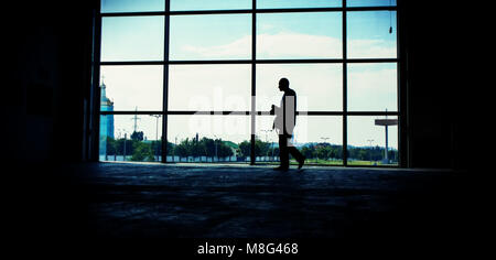 man walks against the window in the room. The summer season, the city. Panoramic and web banner format. Stock Photo