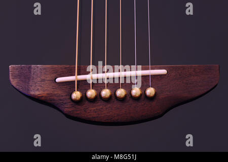 Close-up of a six-string acoustic guitar, ivory bridge, brass bridge pins, and 6 strings. Stock Photo