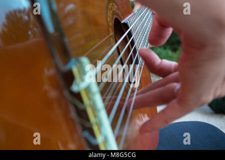 Closeup of a man playing an acoustic guitar in the green Stock Photo