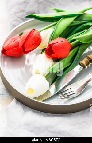 Table setting for Easter dinner with tulips and eggs on white wooden table Stock Photo