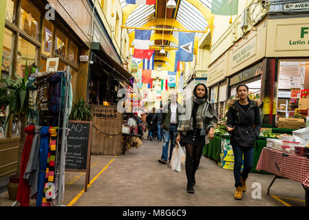 People shopping in the indoor Brixton Village Market, a multicultural community market with independent shops and ethnic restaurants in South London. Stock Photo