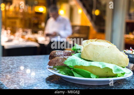 A choripan sandwich with lettuce and french white bread on a counter at Mercado Del Puerto, Montevideo, Uruguay. Stock Photo