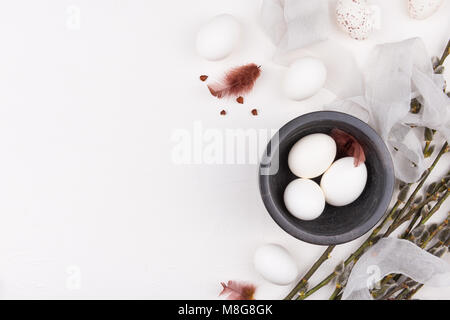 Stylish background with white eggs in black bowl, silk fabric and goat willow branches with space for text. Isolated on white background. Flat lay. Stock Photo