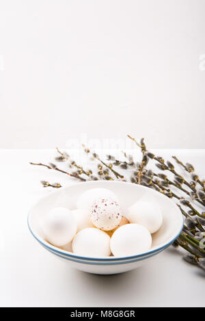 White eggs in bowl, and goat willow branches on a white table and white background. Easter concept. Stock Photo