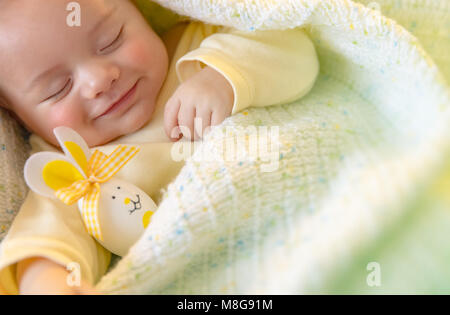 Closeup portrait of a cute little baby sleeping with decorative egg toy, traditional symbol of Easter holiday, love and religion concept Stock Photo