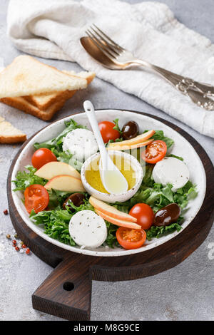 Fresh, delicious goat's cheese salad with lettuce, cherry tomatoes, Apple, Kalamata olives and a dressing of olive oil and toasted bread Stock Photo