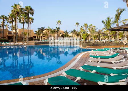 Hotel Poolside Empty Rattan Sunbeds Near Swimming Poll With Calm Blue Crystal Clear Water And Concrete Paving Floor Stock Photo