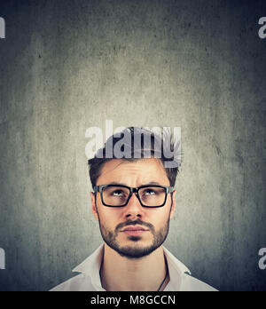 portrait of a young doubtful man with glasses looking up Stock Photo