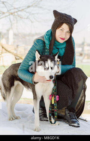 Portrait of stylish woman wearing funny hat and her Siberian husky pet dog Stock Photo