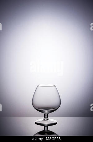 Empty brandy glass backlit on graduated background Stock Photo