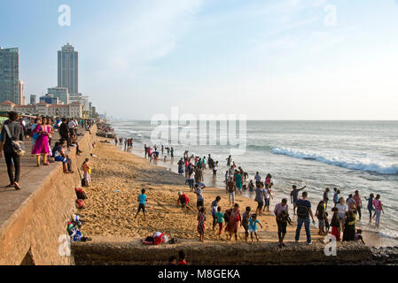 Local people on the beach by Galle Face Green - a popular spot in Colombo to spend time playing and messing about by the sea. Stock Photo