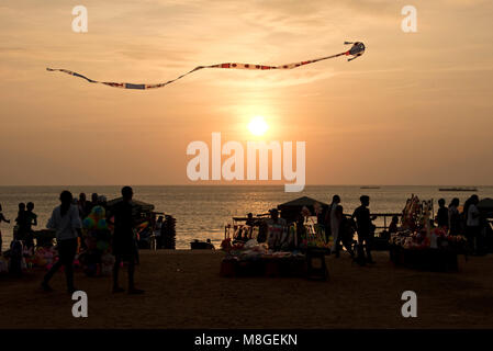 Local people and stall holders with a kite in the air on Galle Face Green at sunset - a popular spot in Colombo to spend time playing by the sea. Stock Photo