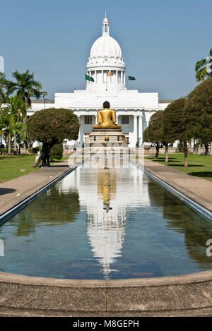 The Town Hall Colombo aka Columbo Town Hall reflected in the water pool inside Viharamahadevi Park with the golden Buddha statue in front. Stock Photo