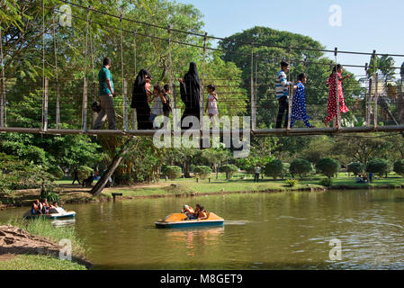 Local people and children in the Viharamahadevi Park (Vihara maha devi) boating lake on a sunny day with blue sky. Stock Photo