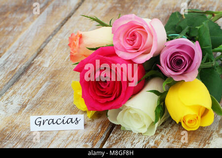 Gracias (thank you in Spanish) card with colorful rose bouquet on rustic wooden surface Stock Photo