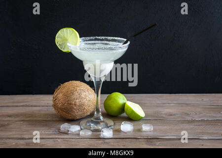 Coconut Margarita Сocktail with lime on dark wooden table, copy space. White Margarita or Daiquiry Cocktail. Stock Photo