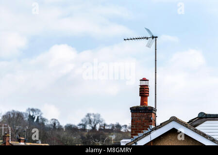 English brick chimney and TV antenna on lovely light blue sky. Stock Photo