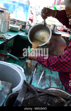 Indian man Chai Wallah pouring chai into a glass at a street food stall Udaipur Rajashan India Stock Photo