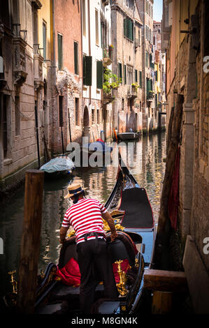 Gondola in Venice, Italy with Italian Gondola Driver preparing his boat on the Venetian Canal Stock Photo