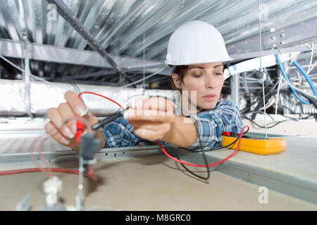 female electrician working on ceiling cables Stock Photo
