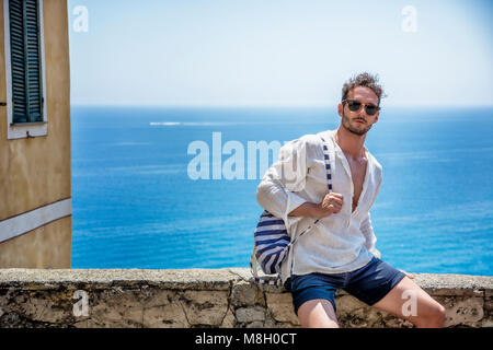 Handsome man sitting at seaside town Stock Photo