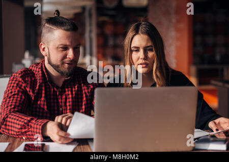 young freelancers man and woman sitting in a cafe and working for a laptop Stock Photo