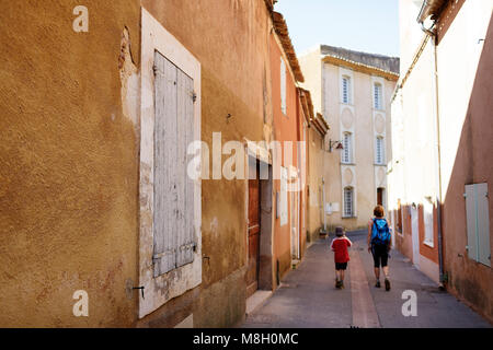 Mother and son walking on picturesque street of Provencal village of Roussillon, Provence, France Stock Photo