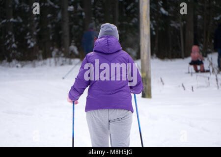 Girl skiing during snowfall weather ski resort Skier wears a blue winter coat, purple hot pants, blue shorts and white gloves. The tree covers the sno Stock Photo