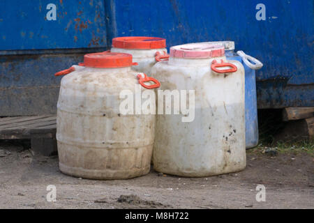 Old construction equipment such as white can and blue plastic barrels Stock Photo