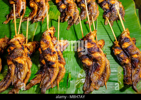 Fried fishes, displayed on banana leaves, on skewers are for sale at Nonthaburi Market Stock Photo