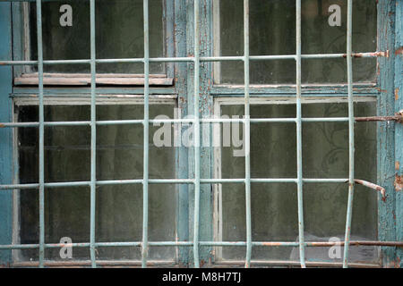 A gloomy window with a lattice in a concrete wall Stock Photo
