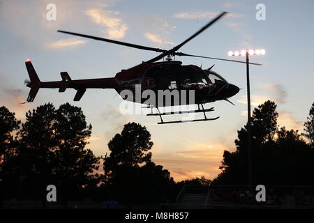 Helicopter delivers the game ball at a Friday night football game. Stock Photo