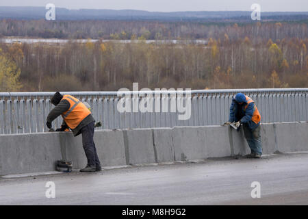 architecture and home renovation concept - man in helmet and gloves with blueprint in factory Stock Photo