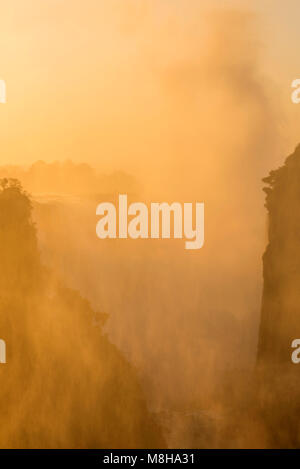 The golden glow of a sunrise over Victoria Falls in Zimbabwe. Stock Photo