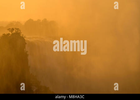 The golden glow of a sunrise over Victoria Falls in Zimbabwe. Stock Photo