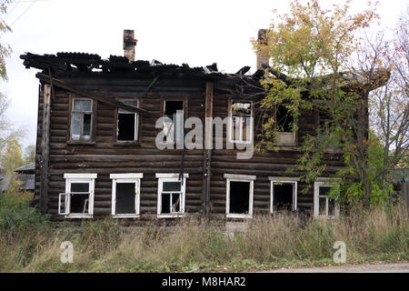 The facade of an wooden house damaged by a fire. The burnt section of the building Stock Photo