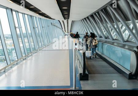 Passengers with luggage walk on a long horizontal escalator covered by a modern tunnel at London Gatwick's North Terminal, England, UK Stock Photo