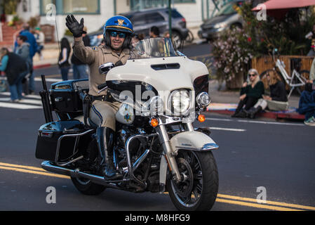 California Highway Patrol officer on motorcycle waves to crowd during annual Saint Patrick's Day Parade in Ventura, California on March 17, 2018 in Un Stock Photo