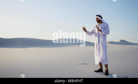 Cheerful Arabian Sheikh male tourist calls friend on Videocall b Stock Photo