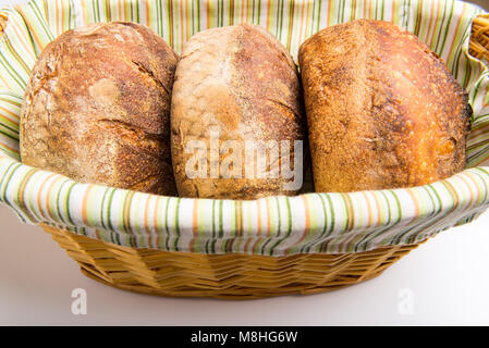 Fresh baked loafs of round artisan sour dough bread in a bread basket. Stock Photo