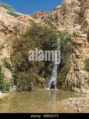 bather enjoying a natural massage in wadi David waterfall at Ein Gedi Stock Photo