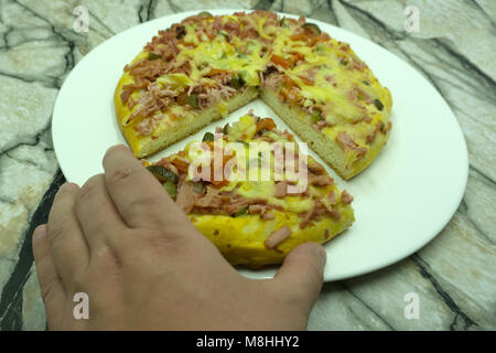 Friends sharing a delicious pizza on a rustic table, they are holding a slice, top view Stock Photo