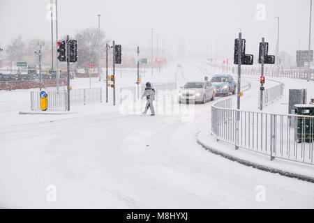 Hereford, Herefordshire, UK - Sunday 18th March 2018 - Hereford city heavy snowfall overnight continues during Sunday morning in Hereford city - a pedestrian crosses on snow covered roads. Steven May /Alamy Live News