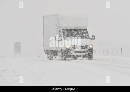 Long Bredy, Dorset, UK.  18th March 2018.  UK Weather.  A van struggles for grip up the hill in blizzard Conditions on the A35 at Long Bredy between Bridport and Dorchester in Dorset as heavy snow which has covered the road, makes driving hazardous.  Picture Credit: Graham Hunt/Alamy Live News. Stock Photo