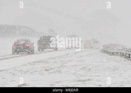 Long Bredy, Dorset, UK.  18th March 2018.  UK Weather.  Vehicles struggles for grip up the hill in blizzard Conditions on the A35 at Long Bredy between Bridport and Dorchester in Dorset as heavy snow which has covered the road, makes driving hazardous.  Picture Credit: Graham Hunt/Alamy Live News. Stock Photo