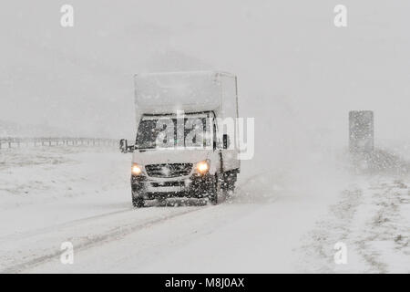 Long Bredy, Dorset, UK.  18th March 2018.  UK Weather.  A van struggles for grip up the hill in blizzard Conditions on the A35 at Long Bredy between Bridport and Dorchester in Dorset as heavy snow which has covered the road, makes driving hazardous.  Picture Credit: Graham Hunt/Alamy Live News. Stock Photo