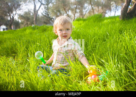Cute baby boy with Easter eggs on a green lawn Stock Photo