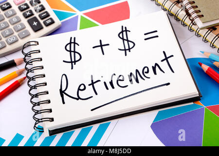 Simple retirement formula written on a notepad surrounded by graphs, charts, calculator, books and pencils. Stock Photo