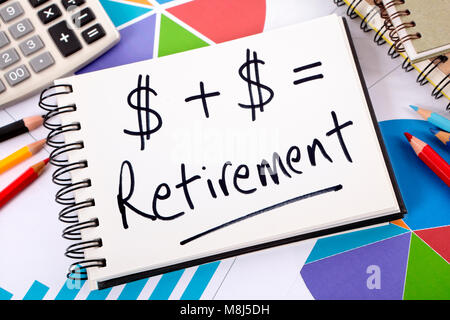 Simple retirement formula written on a notepad surrounded by graphs, charts, calculator, books and pencils. Stock Photo